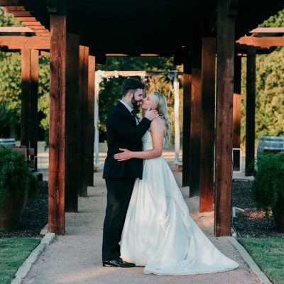 Romantic nighttime couple portrait under wooden pergola walkway at Milagro Venue Texas