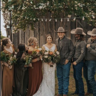 Western wedding party with earth tone bridesmaid dresses and cowboy hats at Milagro Venue Texas
