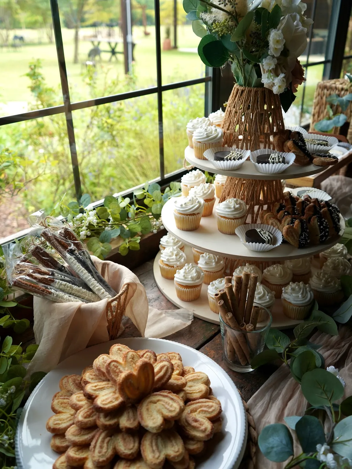 Dessert table with cupcakes, palmeritas and chocolate pretzels by a window overlooking the gardens at Milagro Ranch Venue
